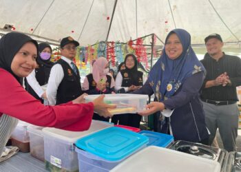 DR. Razan Ab. Samad (kanan) menyampaikan penghargaan kepada salah seorang peniaga amalan bersih di Bazar Ramadan Pantai Irama, Bachok, Kelantan, semalam, UTUSAN/TOREK SULONG