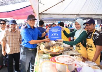 Zaini Hussin (dua kiri) menyerahkan bahan kempen kebersihan kepada peniaga bazar Ramadan di Mydin Mall Tunjong, Kota Bharu, Kelantan hari ini-UTUSAN/KAMARUL BISMI KAMARUZAMAN