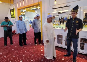 TUAN Ibrahim Tuan Man (kanan) mendengar penerangan operasi Raja Perfume Malaysia daripada pemiliknya Wan Mohd. Raimiey Syazerin semasa melawat premis berkenaan di Kampung Lepar Limbat, Kota Bharu, Kelantan semalam. UTUSAN/MUSTAQIM MOHAMED