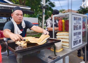 MUHAMMAD Tarmizi Mohd. Nasir sedang menyediakan roti john di gerainya di Bazar Ramadan Peringgit, Bukit Peringgit, Melaka. - UTUSAN/MUHAMMAD SHAHIZAM TAZALI
