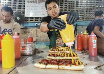 MUHAMAD Azlam Abdul Majid menyediakan roti John yang ditempah pelanggannya di Kampung Kubang Jela, Manir, Kuala Terengganu. – UTUSAN/KAMALIZA KAMARUDDIN