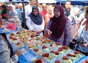 FUZIAH Salleh meninjau para peniaga selepas merasmikan Kempen MYSaveFood di BRR Bandar Baru Merlimau, Jasin, Melaka. - UTUSAN/AMRAN MULUP