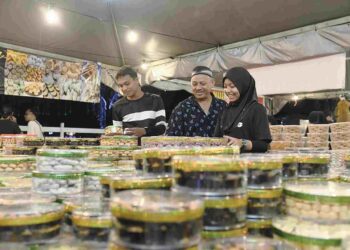 MOHD. Naim Hassan melayan pelanggan yang membeli kuih raya di gerainya di bazar Aidilfitri di Dataran Dato’ Sheikh Ahmad, Kangar, Perlis, semalam. – mingguan/IZLIZAN OTHMAN