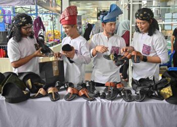 MUHAMAD Rafi Kori (dua dari kanan) bersama tiga adiknya menunjukkan capal buatan tangan yang dijual di Pusat Dagangan Terengganu, Kuala Terengganu, semalam. – UTUSAN/PUQTRA HAIRRY ROSLI