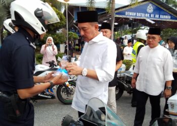 MUHAMAD Zaki Harun (kanan) menyampaikan bubur lambuk kepada salah seorang anggotanya di Ibu Pejabat Polis Kontinjen (IPK) Kelantan, Kota Bharu, Kelantan semalam-UTUSAN/ROHANA MOHD.NAWI
