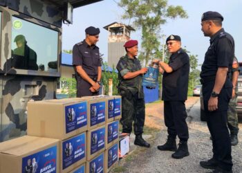 WAN Hassan Wan Ahmad (dua kiri) menyerahkan sumbangan kuih raya kepada wakil pegawai dan anggota Batalion 18 Pasukan Gerakan Am (PGA) yang bertugas menjaga keselamatan di sempadan negara Bukit Kayu Hitam, Kubang Pasu.