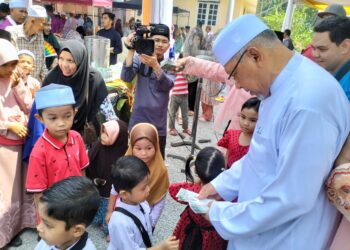 AHMAD Yakob (kanan) memberikan sumbangan duit raya kepada kanak-kanak yang hadir ke rumah terbukanya di Kampung Alor Pasir, Wakaf Bharu, Tumpat, Kelantan-UTUSAN/ROHANA ISMAIL