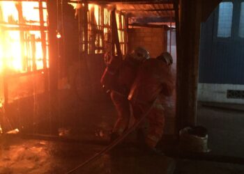 ANGGOTA bomba berusaha memadamkan kebakaran melibat sebuah kereta dan rumah yang dipercayai berpunca daripada mercun dalam kejadian di Kampung Ayer Lanas, Jeli, Kelantan semalam.-UTUSAN/IHSAN BOMBA