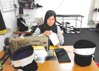 NOR WAHIDA Yaakob menyiapkan tempahan songkok di kedai Songkok ZW di Duyong, Melaka.