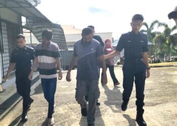 S. Ragubalan (dua dari kanan) dibawa ke Mahkamah Majistret Kuala Pilah, hari ini bagi didakwa atas kesalahan mendatangkan kecederaan kepada isterinya di Tampin pada 24 April lalu.-UTUSAN/NOR AINNA HAMZAH.