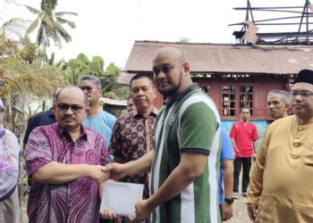 SHAMSUL Iskandar Md Akin menyerahkan sumbangan daripada Perdana Menteri, Datuk Seri Anwar Ibrahim kepada Muhammad Al-Hafiz ketika mengunjungi keluarga mangsa kebakaran di Kampung Tanjong, Gadong, Rembau petang tadi.-UTUSAN/NOR AINNA HAMZAH.