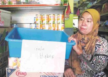SURAYA Harun menunjukkan bekas tempat gula kosong kerana bekalan gula terputus di kedai runcitnya di Kampung Kayu Tinggi Bunut Susu, Pasir Mas, Kelantan.UTUSAN/ROHANA ISMAIL.