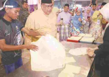 ketua Menteri Melaka Datuk Ab. Rauf Yusoh (tengah) bertanyakan sesuatu kepada Nurul Syafiqah Ali ketika meninjau kiosk roti canai pada Majlis Rumah Terbuka Aidilfitri Kerajaan Negeri yang berlangsung di MITC, Ayer Keroh, Melaka.