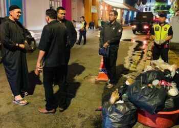 SHADAN Othman (kiri) sedang berbincang dengan pegawai MBMB mengenai sikap degil peniaga dan pemilik premis meletakkan sampah di bahu jalan di Jonker Walk, Banda Hilir, Melaka. - UTUSAN/AMRAN MULUP