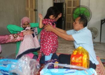 RAZAK Daud (kanan) memakaikan baju baharu kepada kanak-kanak OKU, Ainul Mardhiah Nurul Ridzuan di Felda Kota Gelanggi 2, Jerantut, Pahang. - UTUSAN/SALEHUDIN MAT RASAD
