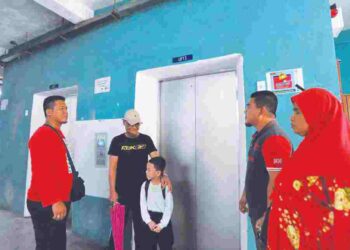 Hendry Gunawan Alias Amri (kiri) bersama penduduk  menunggu pintu lif dibuka di Blok G PPR Kempas Johor Bahru. – UTUSAN/RAJA JAAFAR ALI
