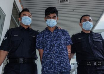 TERTUDUH diiring keluar anggota polis selepas dihadapkan ke Mahkamah Majistret, Ayer Keroh, Melaka atas pertuduhan menyebabkan kematian Sa’adon Sahat pada Februari lalu. - UTUSAN/SYAFEEQ AHMAD