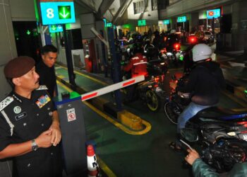 RUSLIN Jusoh (kiri)  melihat kelancaran  penunggang motosikal  melakukan imbasan pasport dan cap jari  di kaunter  imigresen   sebelum memasuki Singapura di  Bangunan Sultan Iskandar, Johor Bahru di sini. UTUSAN/RAJA JAAFAR ALI