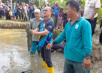 NGWE Hee Sem (dua dari kanan) memegang ikan keli seberat lima kg yang berjaya ditangkap dengan tangan di Kampung Solok Batu Dinding, Kuala Sungga, Melaka. - UTUSAN/AMRAN MULUP