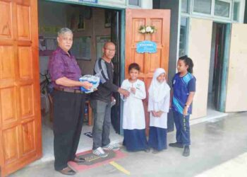 WALIK a/l Ting (dua dari kiri) dan diiringi Guru Besar, Abd Manaf Mat (kiri) mengagihkan sumbangan air mineral daripada PIBG kepada murid Orang Asli etnik Jahut di SK Sungai Kiol, Jerantut, Pahang baru-baru ini.
