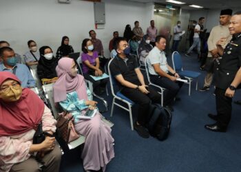 MUHAMMAD Syahmi (kanan) menyantuni wakil majikan yang berkunjung ke kaunter RTK Jabatan Imigresen Malaysia di Kompleks PKNS, di Shah Alam, Selangor. - UTUSAN/ABDUL RAZAK IDRIS