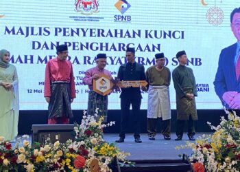 M. Noor Azman Taib (tiga dari kiri) menyerahkan replika kunci rumah kepada penerima pada Majlis Penyerahan Kunci dan Penghargaan Rumah Mesra Rakyat (RMR) SPNB di Hotel Perdana, Kota Bharu, Kelantan hari ini. UTUSAN/ROSMIZAN RESDI