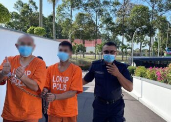 SUSPEK pertama yang juga mudir dan pengasas pusat tahfiz menunjukkan isyarat bagus semasa tiba di pekarangan Kompleks Mahkamah, Ayer Keroh, Melaka.