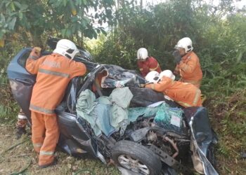ANGGOTA bomba bertungkus lumus mengeluarkan mangsa kemalangan dari sebuah kereta dalam kejadian di Kilometer 33, Jalan Bahau-Keratong, Jempol petang tadi.-GAMBAR/IHSAN BOMBA