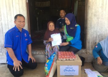 NORA Yaacob (kanan) menyampaikan Faedah Pengurusan Jenazah RM2,000 serta sumbangan kotak prihatin kepada Noryah Awang di rumahnya di Kampung Kemasin, Bachok, Kelantan hari ini. UTUSAN/ROSMIZAN RESDI