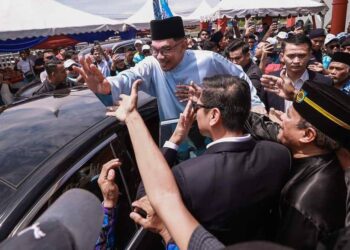 ANWAR Ibrahim mengangkat tangan kepada hadirin yang hadir pada Majlis Sambutan Aidilfitri Perpaduan Madani anjuran Pertubuhan Prihatin Anak Melaka bersama PDRM di Dewan Bunga, Tanjung Minyak, Melaka.