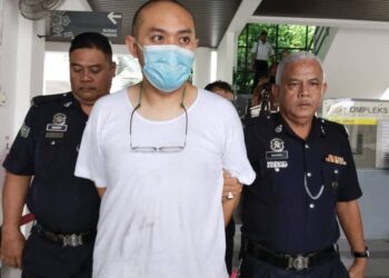 TERTUDUH diiringi anggota polis selepas dihadapkan ke Mahkamah Sesyen di Alor Gajah, Melaka.