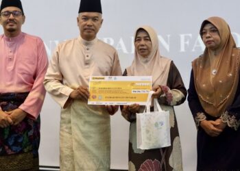 ZALIHA Yunus (dua, kanan) menerima cek faedah pencen penakat daripada Ahmad Nadzarudin Abdul Razak (dua, kiri) pada Majlis Sambutan Hari Raya Aidilfitri Perkeso Peringkat Negeri Terengganu di Kuala Terengganu, semalam. - UTUSAN/TENGKU DANISH BAHRI TENGKU YUSOFF