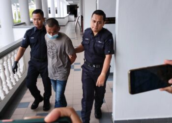 TERTUDUH diiring anggota polis selepas dihadapkan ke Mahkamah Majistret, Ayer Keroh, Melaka. - UTUSAN/MUHAMMAD SHAHIZAM TAZALI