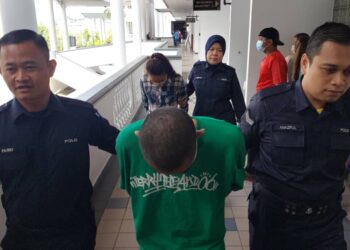 PASANGAN suami isteri diiring anggota polis selepas dihadapkan ke Mahkamah Majistret, Ayer Keroh, Melaka kerana mencuri susu formula. - UTUSAN/MUHAMMAD SHAHIZAM TAZALI