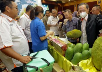 CHAN Foong Hin merasai buahan tempatan ketika membuat lawatan ke gerai pameran selepas merasmikan Seminar Pelaburan Subsektor Tanaman Agromakanan Malaysia di Putrajaya. - UTUSAN/FAISOL MUSTAFA
