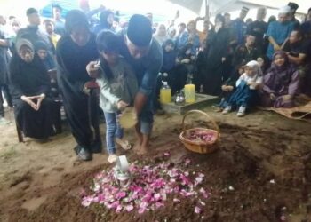 ANAK ketiga Allahyarham Awang Askandar Ampuan Yaacub menyiram pusara ayahnya di Tanah Perkuburan Islam Kampung Benoni di Papar hari ini