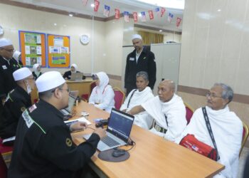 SHAMSUL Bahar Shamsudin (berdiri) memerhatikan petugas TH melayani jemaah yang ingin berurusan di kaunter Bank Islam di Abraj Al-Janadriyah di Mekah.