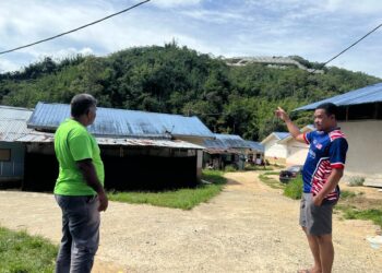 MURAD Mat (kanan) menunjukkan kawasan kebun yang dibuka berhampiran kawasan penempatan Orang Asli Kampung Sengsang di Pos Brooke, Gua Musang, Kelantan.-UTUSAN/AIMUNI TUAN LAH