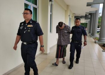 TERTUDUH (tengah) dibawa polis keluar dari Mahkamah Pasir Mas selepas mengaku bersalah menyebabkan dua mangsa kerugian RM 17,500 dalam dua kes penipuan di awal tahun ini-UTUSAN/ROSALWANI CHE SOH