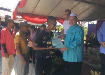 MOHD. Amar Nik Abdullah (kanan) menyampaikan geran kepada penerima pada Majlis Penyampaian Geran Hak Milik Tanah Jajahan Tanah Merah di Masjid Ikhtikad, Kampung Panjang, Tanah Merah, Kelantan hari ini-UTUSAN/ROSMIZAN RESDI
