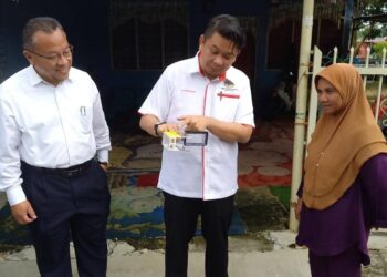 LUKANISMAN Awang Sauni (tengah) menunjukkan nyamuk berbakteria Wolbachia pada program pelepasan di Taman Bemban Jaya, Jasin, Melaka. - UTUSAN/AMRAN MULUP