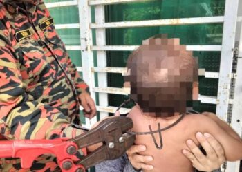 ANGGOTA bomba berusaha memotong besi yang tersangkut pada bahagian leher bayi dalam kejadian di Taman SPP Kota Warisan, Tumpat, Kelantan semalam-UTUSAN/IHSAN BOMBA