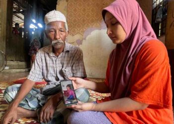 SITI Aminah Awang Mat bersama bapa mentuanya, Che Nah Wachae menunjukkan gambar arwah suaminya di rumah keluarga mentuanya di Kampung Jelekang, Bertam Lama, Gua Musang, Kelantan.UTUSAN/AIMUNI TUAN LAH