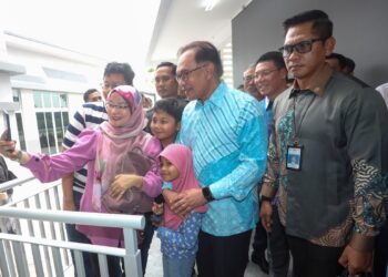 ANWAR Ibrahim bergambar besama penduduk pada majlis penyerahan kunci Perumahan Penjawat Awam Malaysia (PPAM) Dalur Madani di Putrajaya. - UTUSAN/FAISOL MUSTAFA