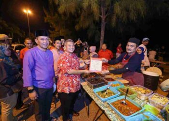 RAIS Yasin menyerahkan lesen berniaga sementara kepada Ramlan Abdul Rahman sambil diperhatikan Shadan Othman di Pantai Eye On, Kota Laksamana, Melaka.