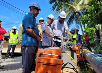 AZAMI Mohd. Nor (dua dari kiri) diberikan penerangan mengenai kelengkapan digunakan untuk kerja penggantian paip AKSB di Pasir Tumbuh, Kota Bharu, Kelantan hari ini. UTUSAN/MUSTAQIM MOHAMED