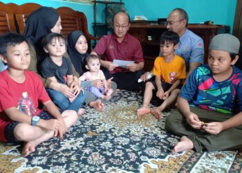 NGWE Hee Sem (tengah) menyampaikan cek pencen penakat kepada Siti Suryati Sani (dua dari kiri) ketika ditemui Skuad Perkeso Prihatin di Taman Sutera Wangi, Batu Berendam, Melaka. - UTUSAN/AMRAN MULUP