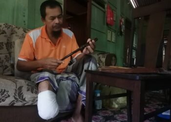 WAN Omar Wan Mansor yang hilang kaki kanan akibat kencing manis melihat sarung pisau hasil tangannya di rumahnya di Kampung Bukit Diman, Ajil, Hulu Terengganu. - NOOR HAYATI MAMAT