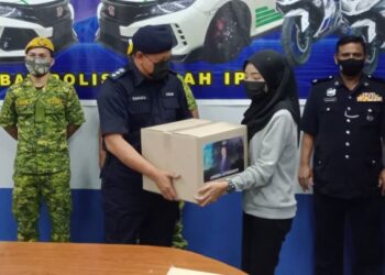 YAHAYA Hassan (kiri) menyampaikan bantuan kotak makanan kepada seorang penerima di Ipoh hari ini.