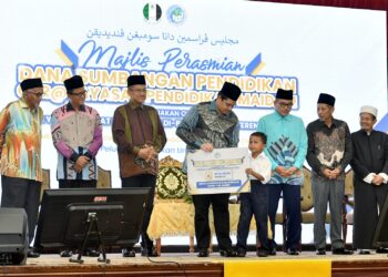 TENGKU Muhammad Ismail Sultan Mizan Zainal Abidin (tengah) menyampaikan Sumbangan Pendidikan YPM di Kuala Terengganu, hari ini. - UTUSAN/KAMALIZA KAMARUDDIN
